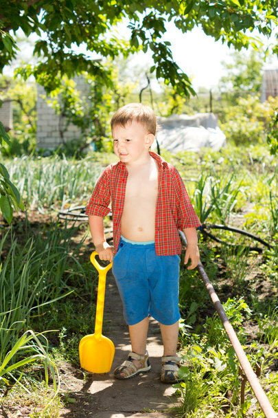 Boy holding a little plastic shovel in a sunny day - Photo, Image