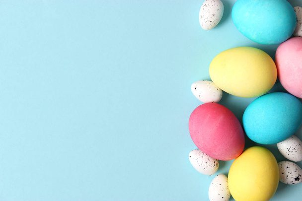 Pääsiäisen koostumus maalattuja munia ja höyheniä värillisellä taustalla. Pääsiäisen tausta
 - Valokuva, kuva
