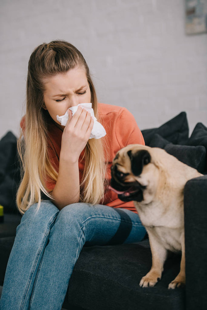 selective focus of girl allergic to dog sitting near cute pug - Foto, afbeelding