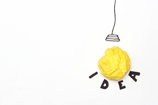 creative concept "idea", a new idea. Painted light bulb with a crumpled paper yellow ball. - Fotografie, Obrázek