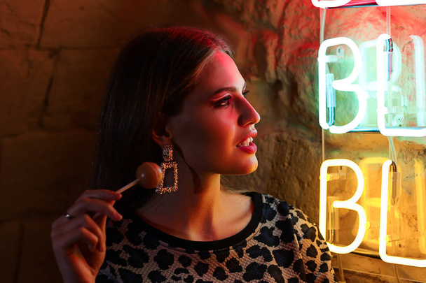 Portrait of beautiful young woman standing near neon lighting on wall - Foto, immagini