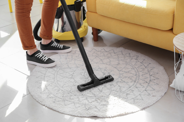 Vrouw schoonmaken tapijt met hoover thuis - Foto, afbeelding