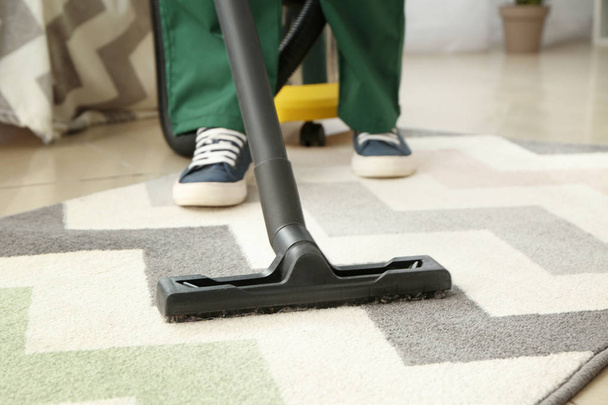 Werknemer schoonmaak tapijt met hoover - Foto, afbeelding