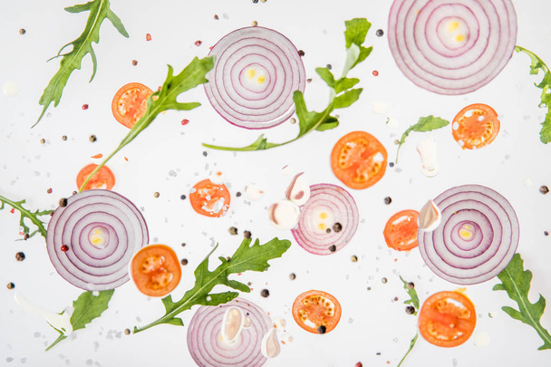 background with sliced tomatoes, red onions, garlic, arugula leaves and spices - Photo, Image