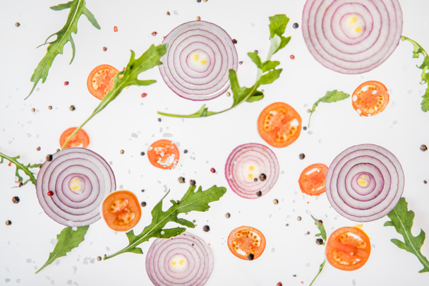 background with sliced tomatoes, red onions, green arugula leaves and spices - Foto, afbeelding