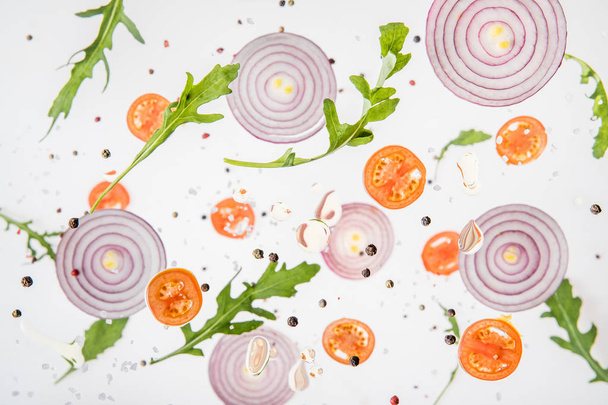 background with sliced tomatoes, red onions, garlic, green arugula leaves and spices - 写真・画像