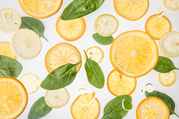 bright orange and lemon slices with green spinach leaves on grey background - Photo, Image