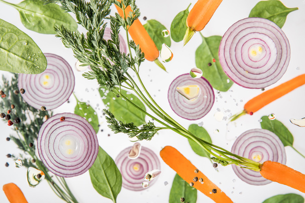 background with carrots, red onions, spices and spinach leaves  - Photo, Image