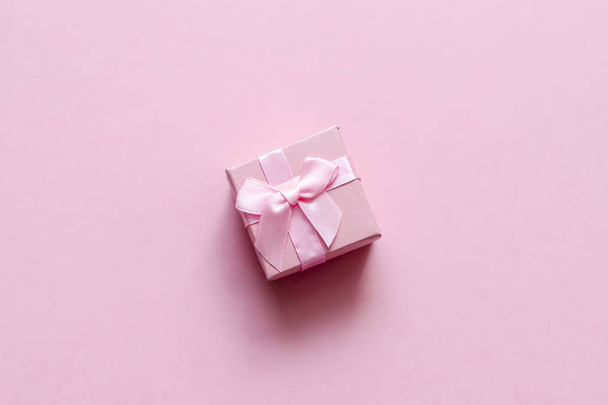 Vaaleanpunainen lahjapakkaus, jossa rusetti vaaleanpunaisella pastellitaustalla. Juhlava taustalevy
 - Valokuva, kuva