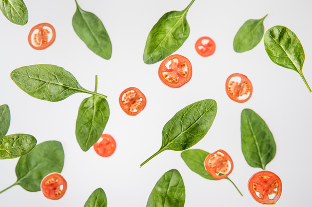 background with sliced tomatoes and green spinach leaves isolated on grey - Photo, Image