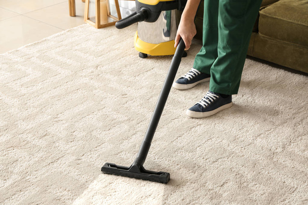 Werknemer schoonmaak tapijt met hoover - Foto, afbeelding