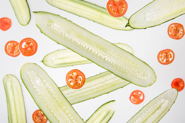 achtergrond met gesneden rode tomaten en komkommers op grijs - Foto, afbeelding