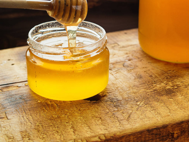 Pot en verre avec miel sucré sur panneau en bois
 - Photo, image