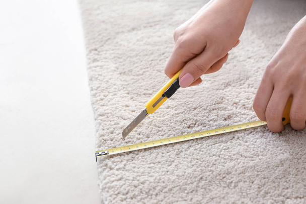 Woman with tape measure cutting carpet - Photo, Image