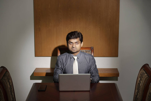 Homme d'affaires indien mature préférant travailler seul à table dans une salle de réunion vide
 - Photo, image