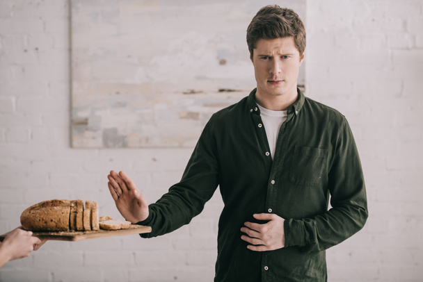 cropped view of woman holding cutting board with bread near handsome man with gluten allergy   - Photo, Image