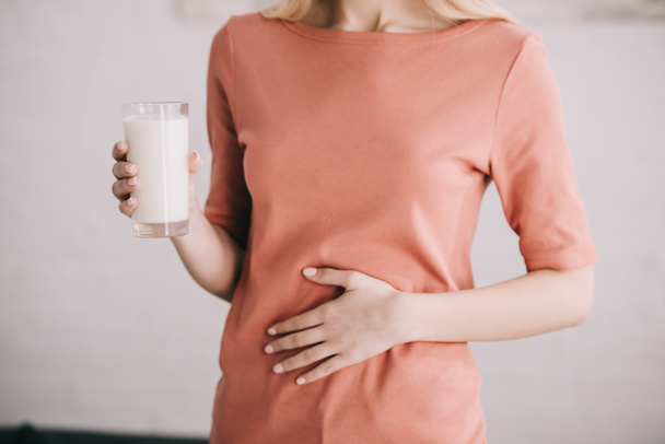 vue recadrée de la femme tenant un verre de lait tout en ayant mal à l'estomac
  - Photo, image
