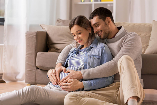 man with pregnant woman making hand heart at home - Valokuva, kuva