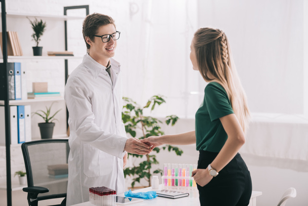 blonde girl shaking hands with doctor in glasses and white coat  - Foto, Imagem