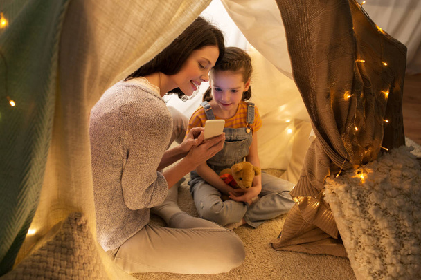 happy family with smartphone in kids tent at home - Foto, afbeelding