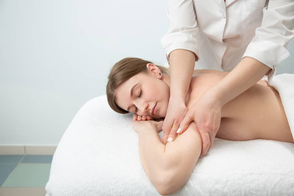 Relaxed woman receiving neck massage in wellness center - Фото, изображение