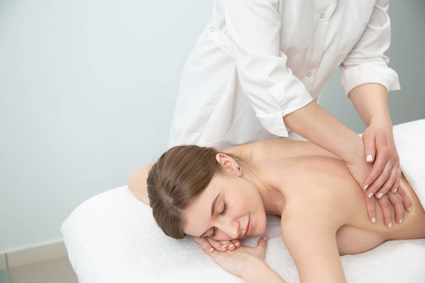 Relaxed woman receiving neck massage in wellness center - Foto, afbeelding