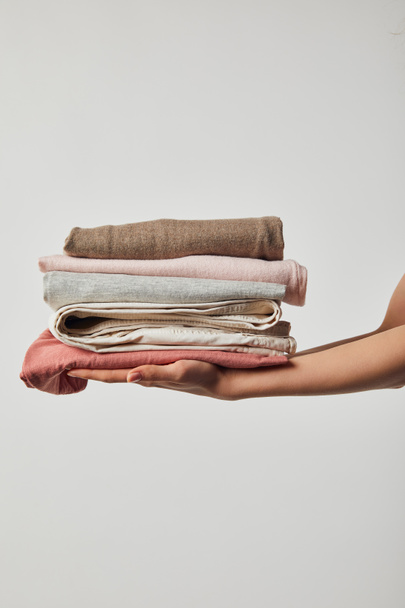 Cropped view of woman holding folded ironed clothes isolated on grey - Photo, Image