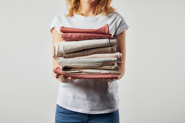 Cropped view of woman holding folded ironed clothes isolated on grey - Photo, Image