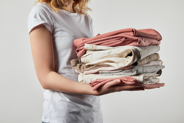Cropped view of woman holding folded ironed clothes isolated on grey - Φωτογραφία, εικόνα
