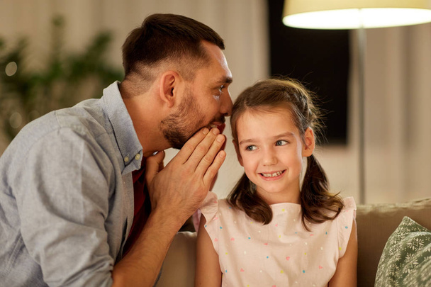 happy father whispering secret to daughter at home - Fotó, kép
