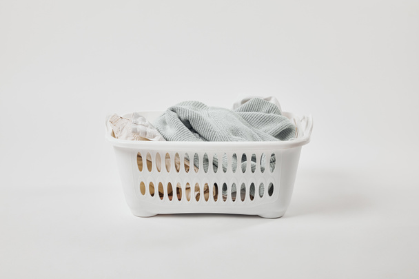 White plastic laundry basket with dirty clothes on grey - Fotó, kép