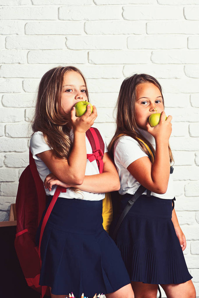 Regreso a la escuela y tiempo feliz Lindos niños comiendo manzanas. Los niños están aprendiendo en clase sobre el fondo de la pared de ladrillo
 - Foto, imagen