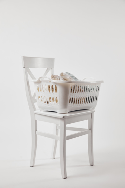 Chaise en bois avec panier à linge en plastique sur blanc
 - Photo, image