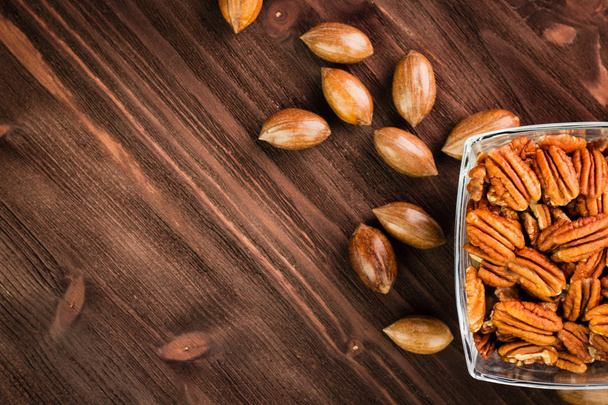 Pekanové ořechy ve skořápce se pekanové jádra na dřevěné pozadí - Fotografie, Obrázek