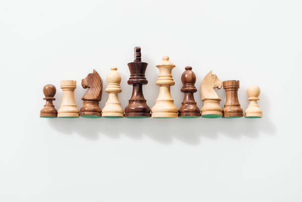 vista superior de la fila hecha de figuras de ajedrez de madera marrón y beige sobre fondo blanco
 - Foto, imagen