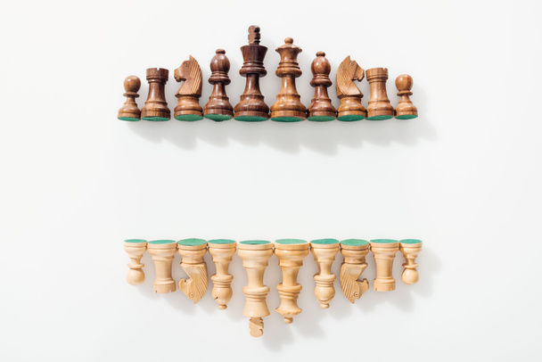 vista superior de filas hechas de figuras de ajedrez de madera marrón y beige sobre fondo blanco con espacio para copiar
 - Foto, Imagen