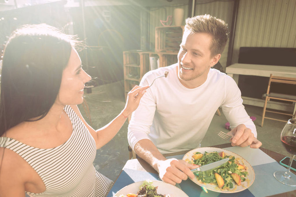Chica atractiva alegre llevando tenedor con comida y proponiéndole matrimonio a su novio
 - Foto, Imagen