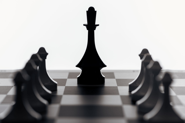 selective focus of chessboard with black queen and pawns isolated on white - Foto, afbeelding