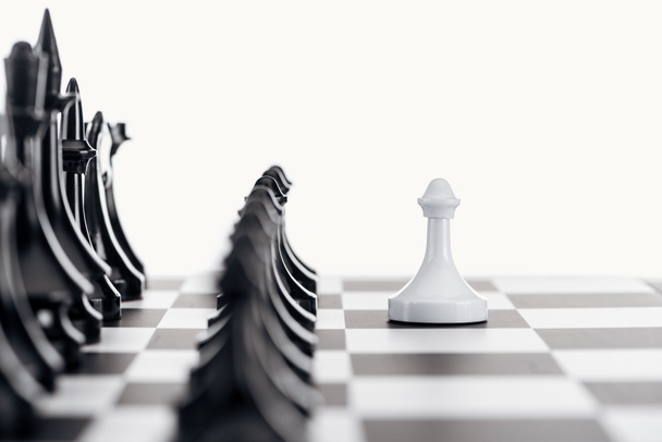 selectieve aandacht van schaakbord met zwarte chess cijfers en witte pion op de voorgrond op wit geïsoleerd - Foto, afbeelding