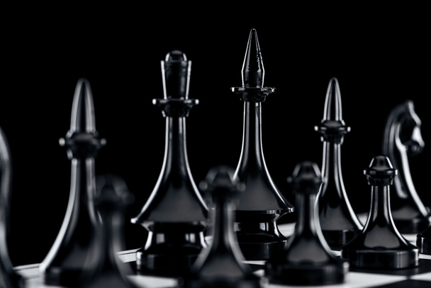 Close up van schaakbord met zwarte chess cijfers geïsoleerd op zwart - Foto, afbeelding