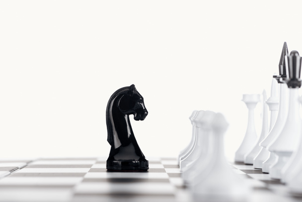 selektiver Fokus des Schachbretts mit weißen Schachfiguren und schwarzem Ritter isoliert auf Weiß - Foto, Bild