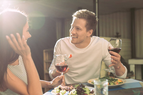 Communicative boyfriend with light stubble eating salad and talking with girl - 写真・画像