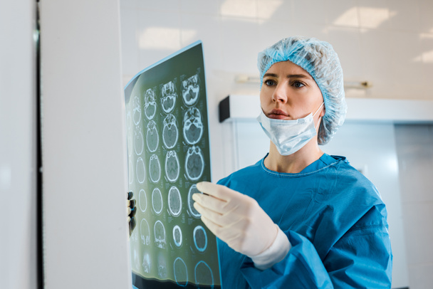 attractive doctor in medical cap and uniform holding x-ray in clinic  - Foto, Imagen