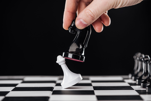 visão parcial do homem fazendo movimento com cavaleiro no tabuleiro de xadrez isolado no preto
 - Foto, Imagem