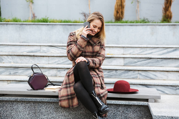 Attractive young woman wearing coat sitting - Foto, Imagem