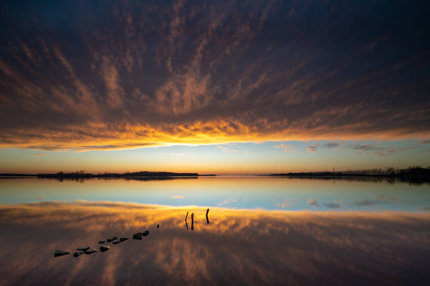 Sfeervolle zonsondergang boven het wateroppervlak met threatenin spiegelen - Foto, afbeelding