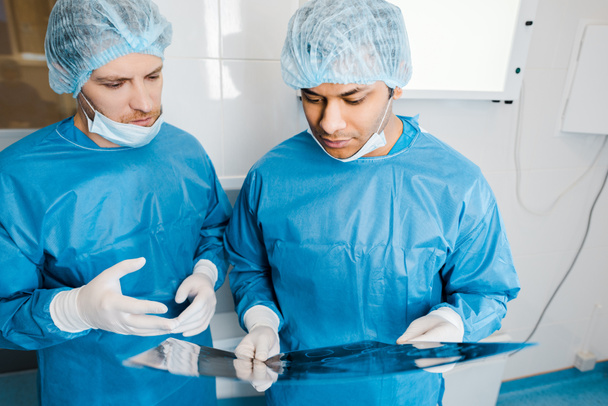 médicos guapos en uniformes y máscaras médicas hablando de rayos X
 - Foto, Imagen