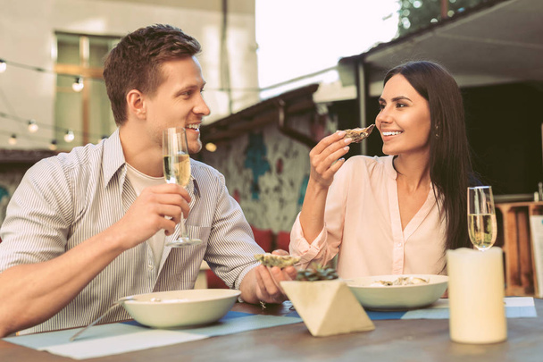 Cheerful young couple eating expensive sea oysters and drinking - Fotografie, Obrázek