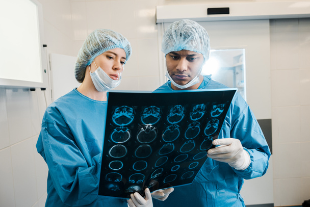 dobře vypadající a krásní doktoři v uniformách a lékařských maskách, jak mluví o rentgenu - Fotografie, Obrázek
