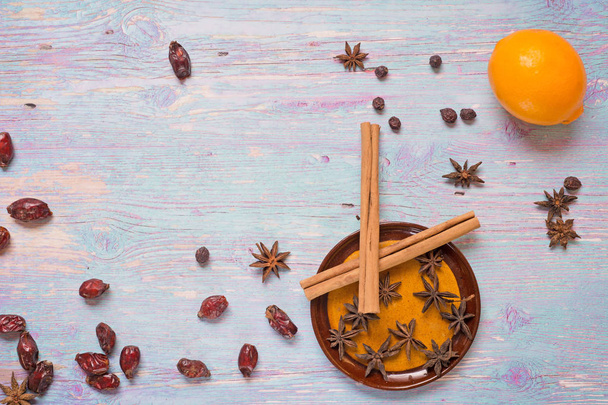blue wooden background with cinnamon, anise, dog rose  and lemon - Foto, afbeelding